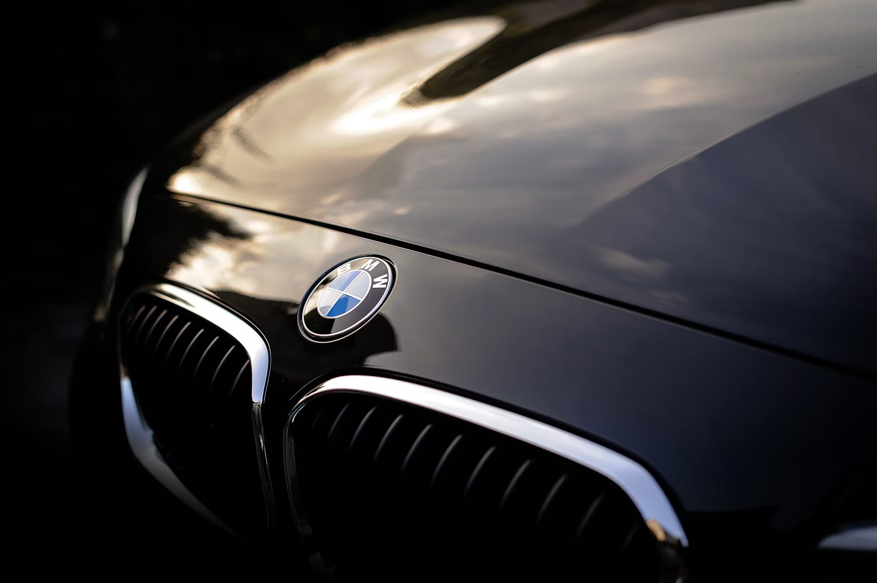 Diepzwarte, gepolijste motorkap van een BMW met spiegelende reflectie